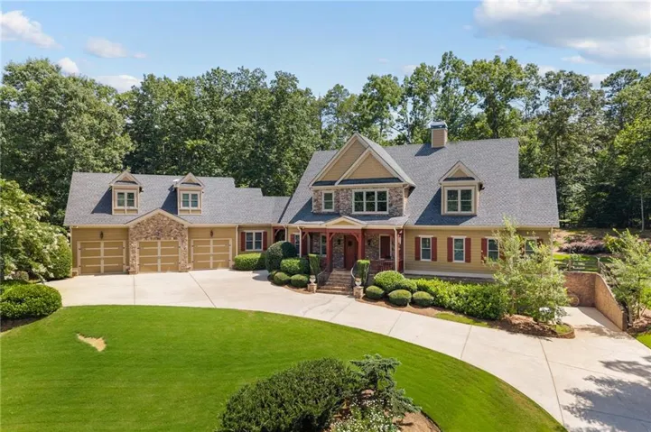 Expansive residence featuring a stone and siding exterior, a multi-car garage, and a concrete driveway