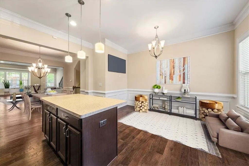 Kitchen with dark hardwood / wood-style floors, pendant lighting, crown molding, and a chandelier