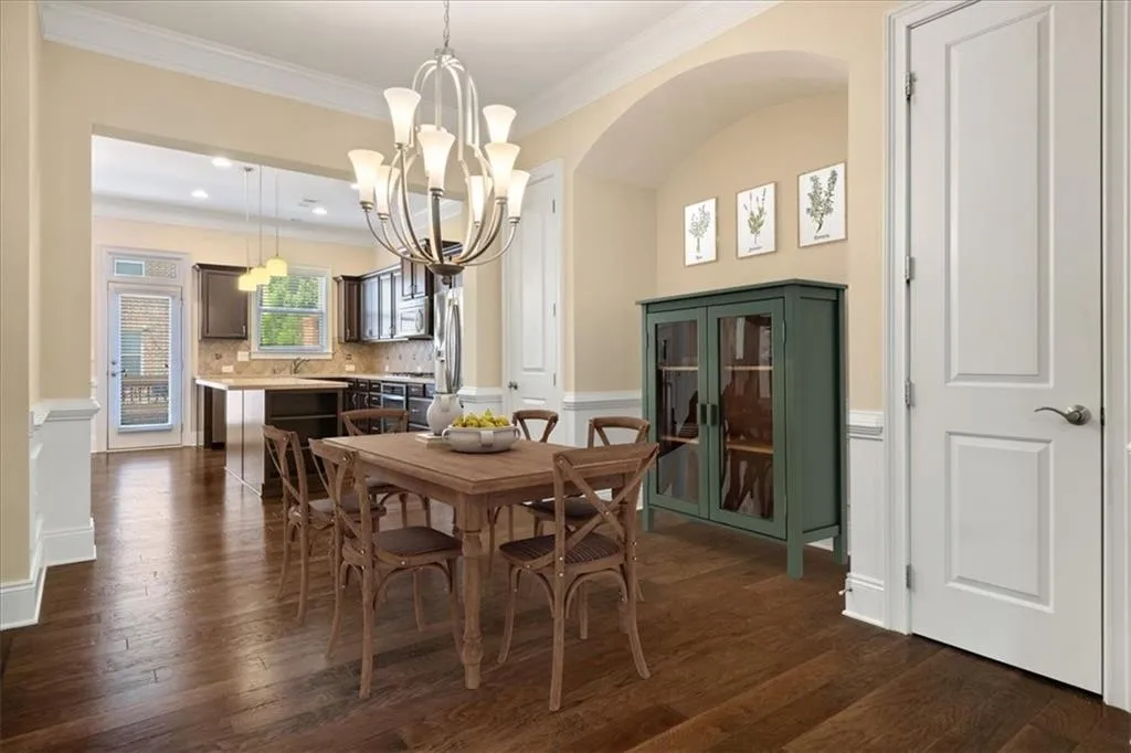 Dining space featuring ornamental molding, dark wood-type flooring, and a chandelier