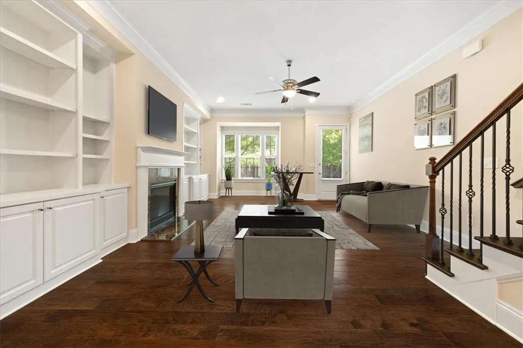 Living room featuring ceiling fan, crown molding, a fireplace, and dark hardwood / wood-style floors