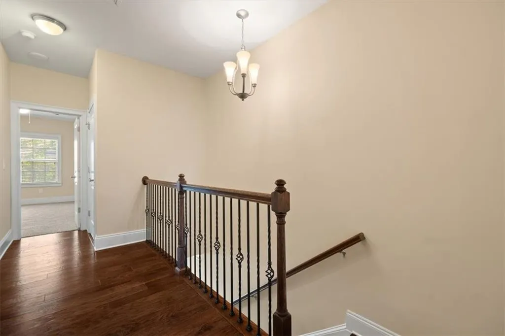 Hall with dark wood-type flooring and a notable chandelier