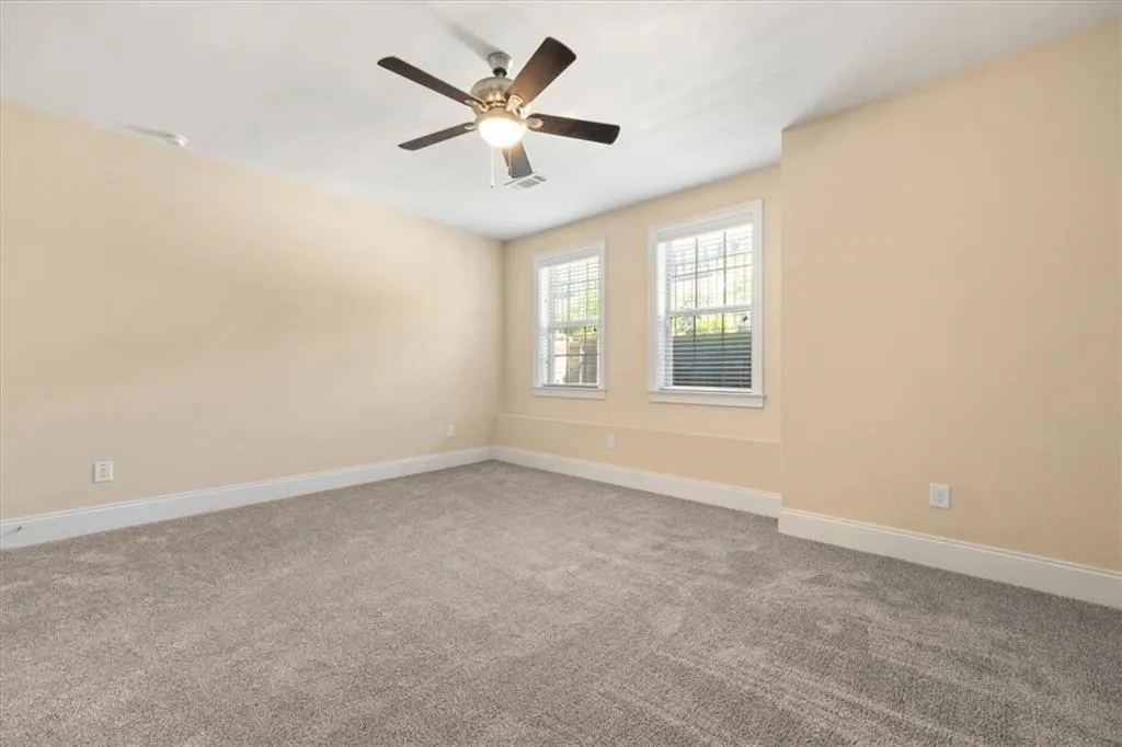Carpeted spare room featuring ceiling fan