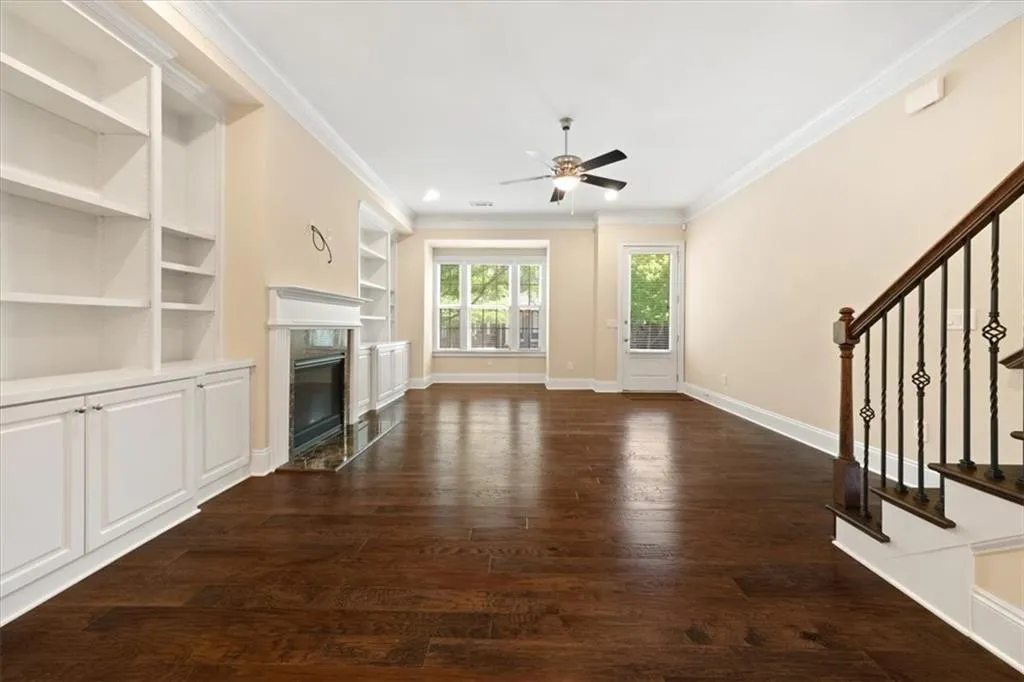 Unfurnished living room with ceiling fan, ornamental molding, dark hardwood / wood-style flooring, and a high end fireplace