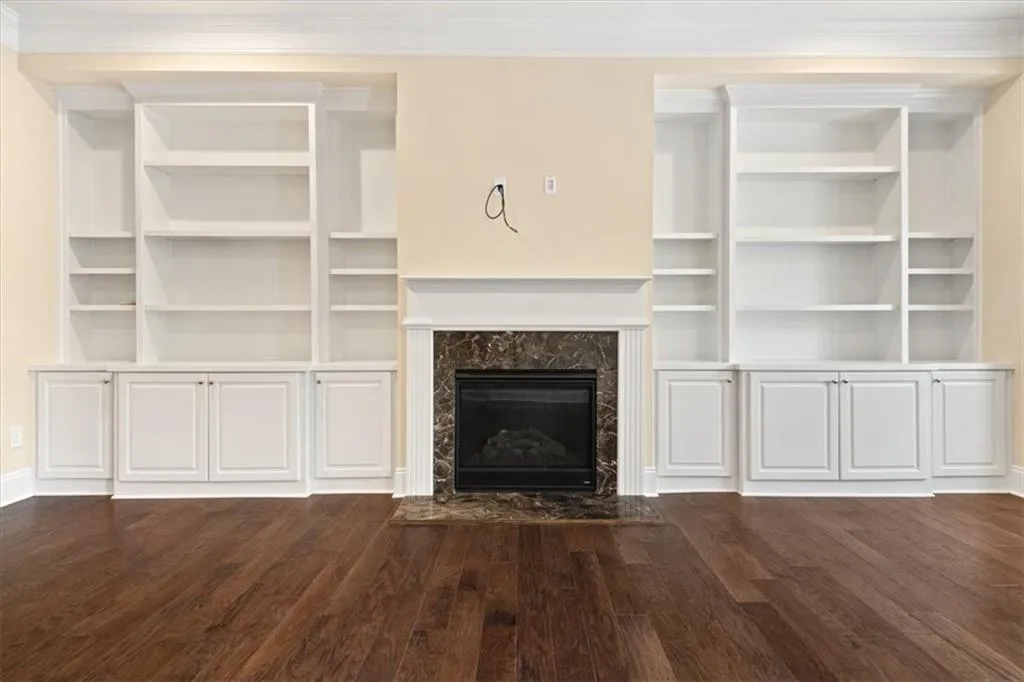 Unfurnished living room featuring ornamental molding, dark hardwood / wood-style flooring, and a high end fireplace