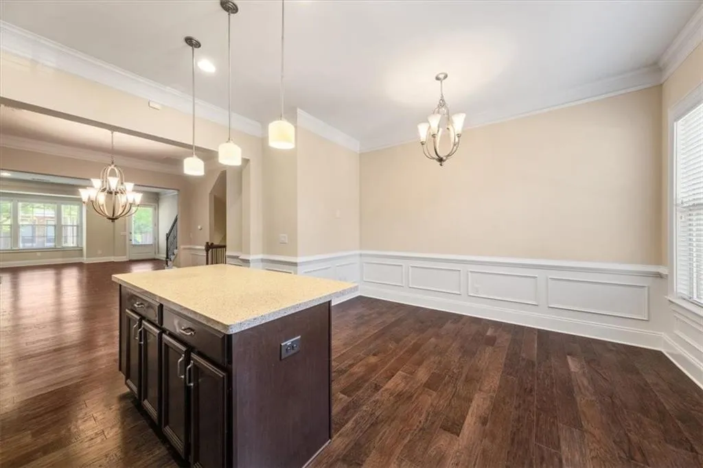 Kitchen featuring hanging light fixtures, dark hardwood / wood-style flooring, a chandelier, and ornamental molding
