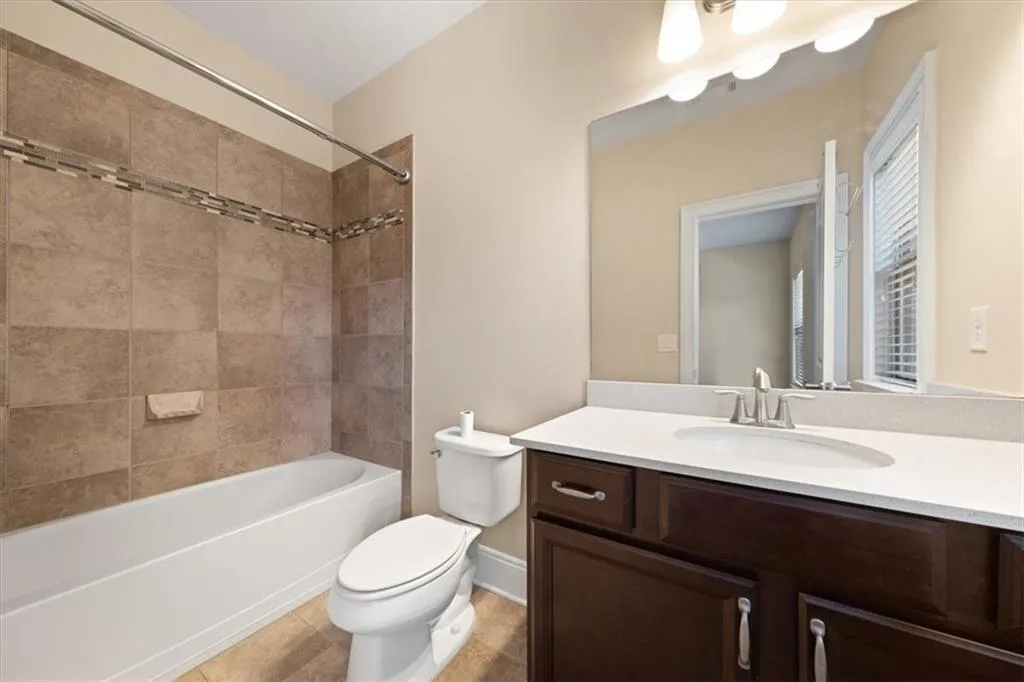 Full bathroom with tiled shower / bath, toilet, tile floors, and vanity