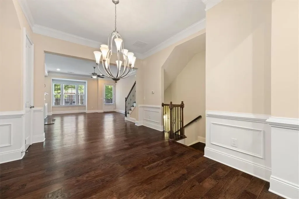 Unfurnished dining area with dark wood-type flooring, an inviting chandelier, and ornamental molding