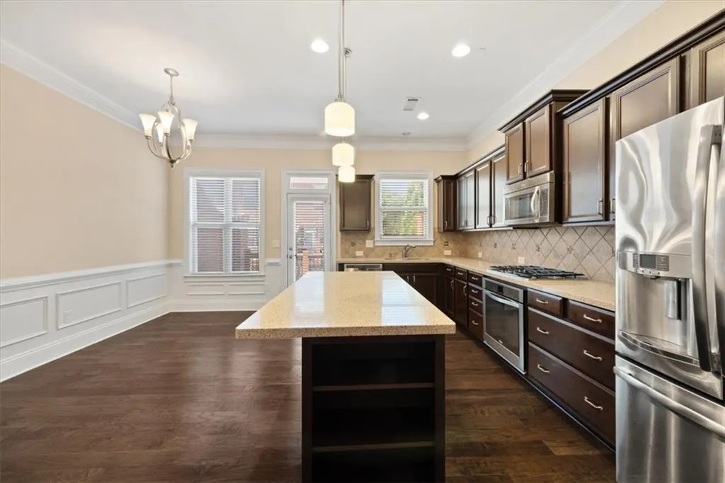 Kitchen with a center island, backsplash, dark hardwood / wood-style flooring, stainless steel appliances, and ornamental molding