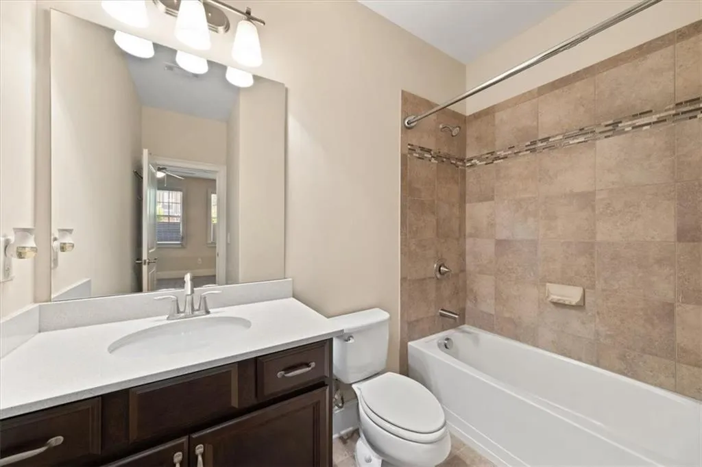 Full bathroom with tiled shower / bath, vanity, and toilet