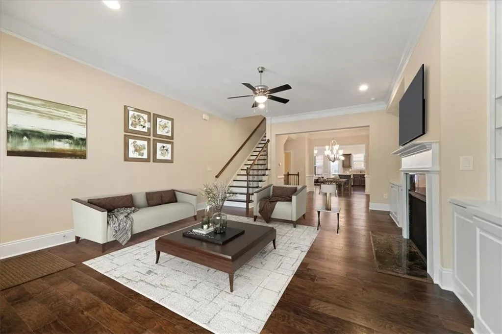 Living room with ornamental molding, ceiling fan with notable chandelier, and hardwood / wood-style floors