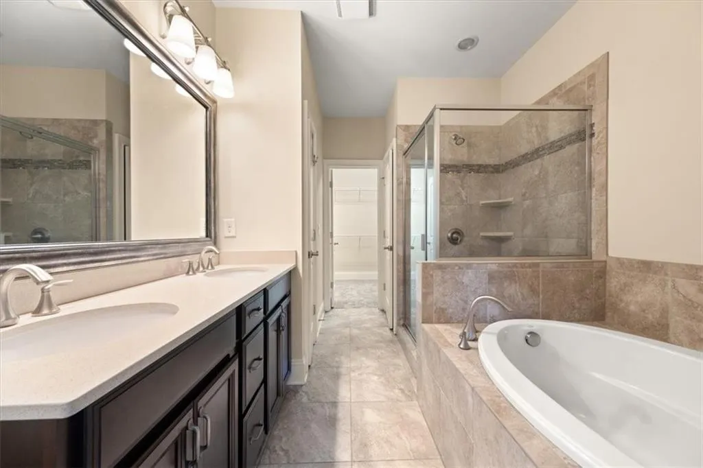 Bathroom with tile flooring, shower with separate bathtub, double sink, and large vanity