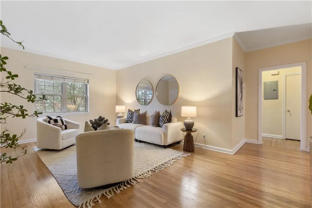 Living room with light wood-style floors, crown molding, and electric panel