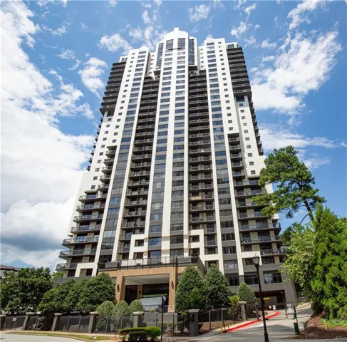Modern high-rise residential building featuring multiple balconies, a structured facade, and a covered entry