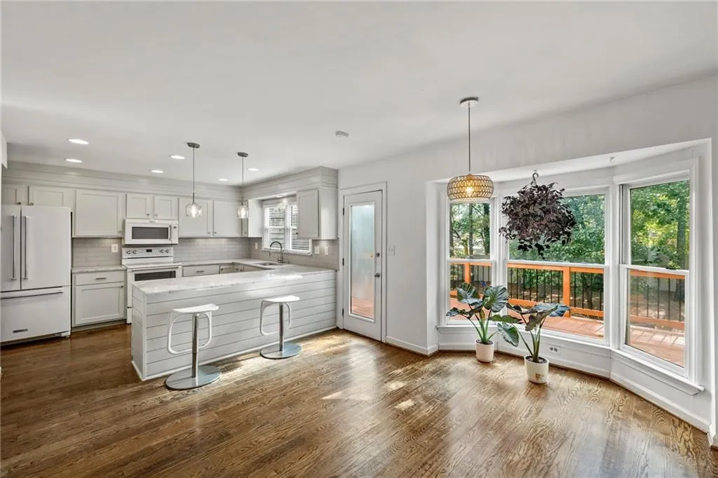 Kitchen featuring white appliances, a peninsula, tasteful backsplash, white cabinetry, and recessed lighting