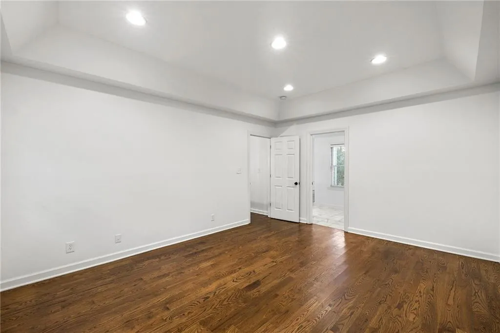 Unfurnished room with a raised ceiling, dark wood-style floors, and recessed lighting