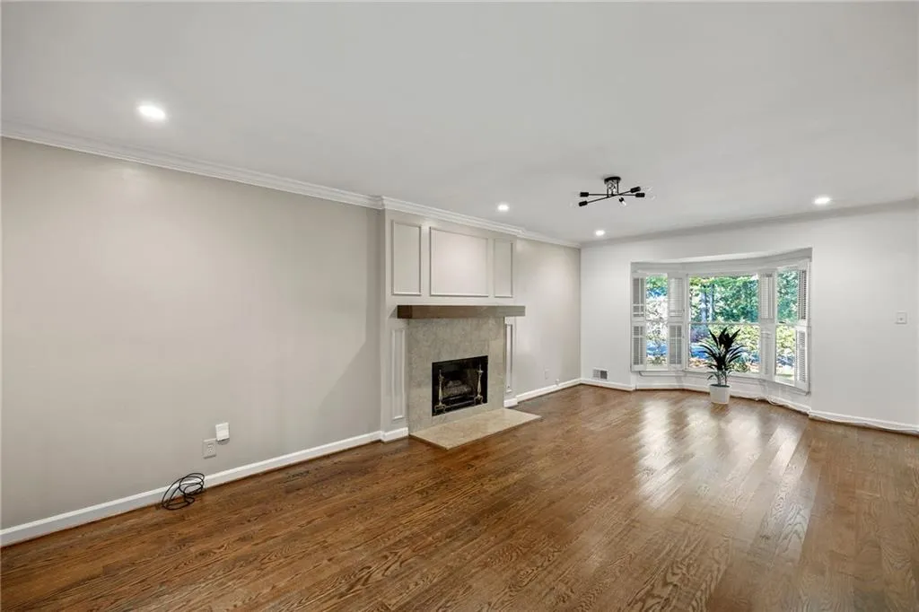 Unfurnished living room featuring ornamental molding, dark wood-style flooring, a fireplace, and recessed lighting