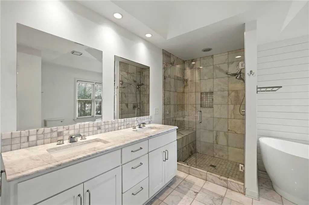 Full bath featuring a shower stall, a soaking tub, double vanity, recessed lighting, and light marble finish floors