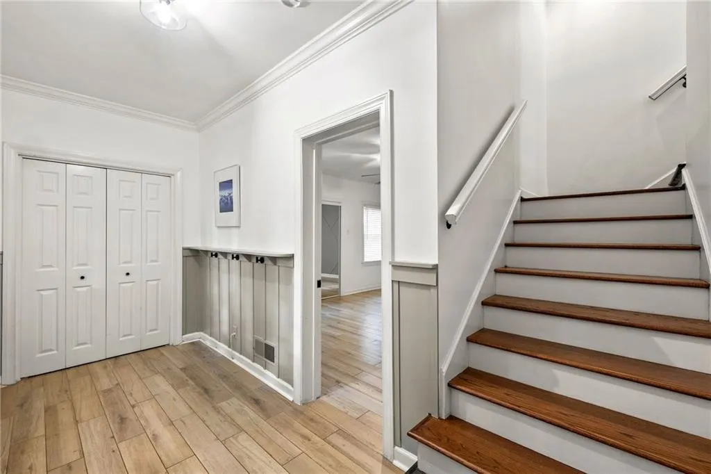 Stairs featuring crown molding and wood finished floors