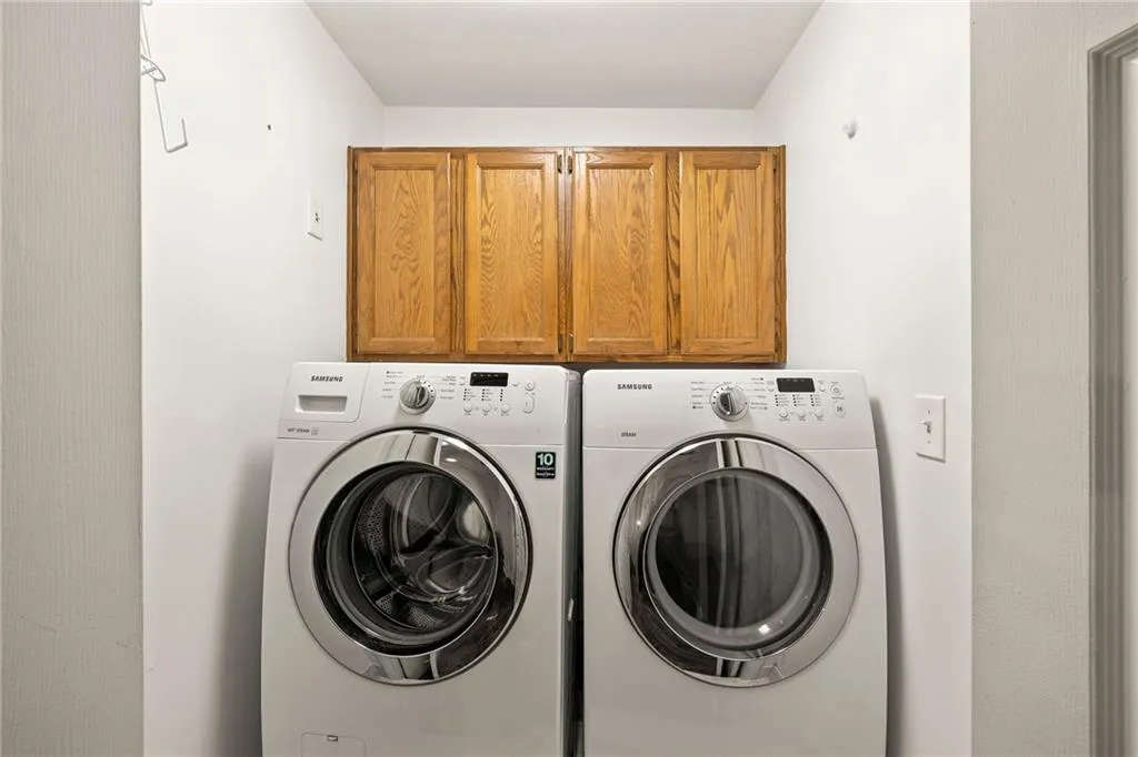 Washroom with washer and clothes dryer and cabinet space