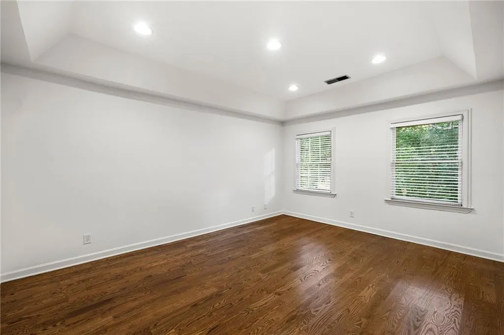 Unfurnished room with a raised ceiling, dark wood finished floors, and recessed lighting