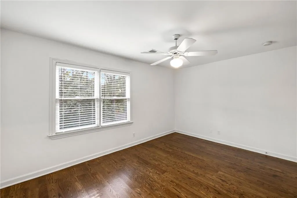 Empty room with dark wood-style flooring and a ceiling fan