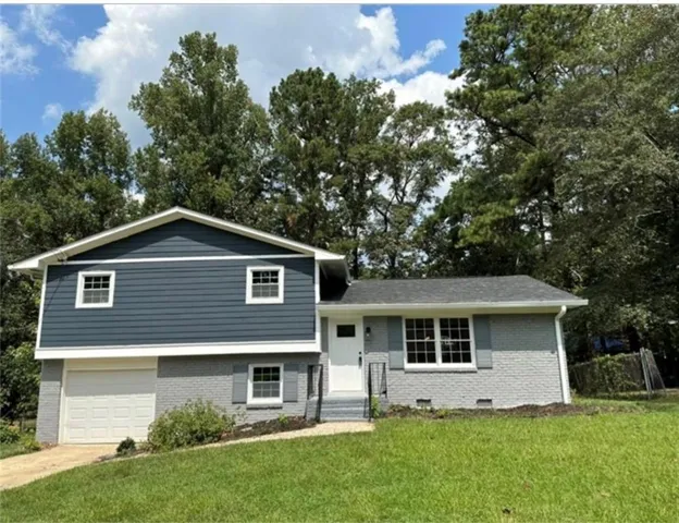 Two-story property featuring a split-level design, painted brick exterior, dark blue siding, and a white garage door