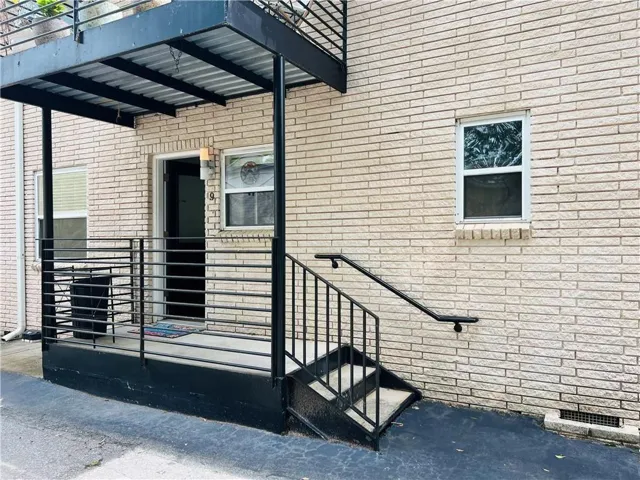 Brick exterior with a covered entry, featuring black metal railings and a staircase
