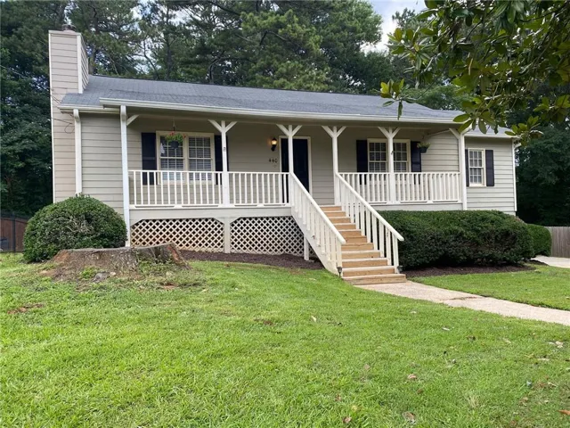 Front exterior with light-colored siding, a covered porch with white railings, and a dark shingled roof