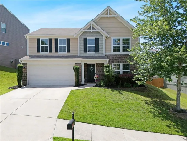 Two-story residence featuring a brick and siding facade, a two-car garage, and a concrete driveway