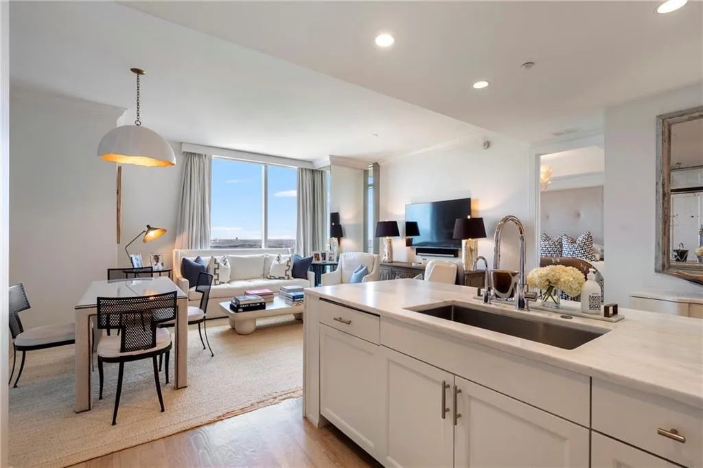 Open-concept living space featuring a kitchen island with an undermount sink, recessed lighting, wood-finish flooring, and expansive windows