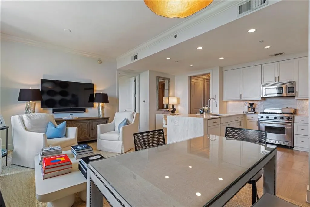 Open-concept living space with recessed lighting, crown molding, a kitchen featuring light wood-finish cabinetry, stainless steel appliances, and an island with an undermount sink