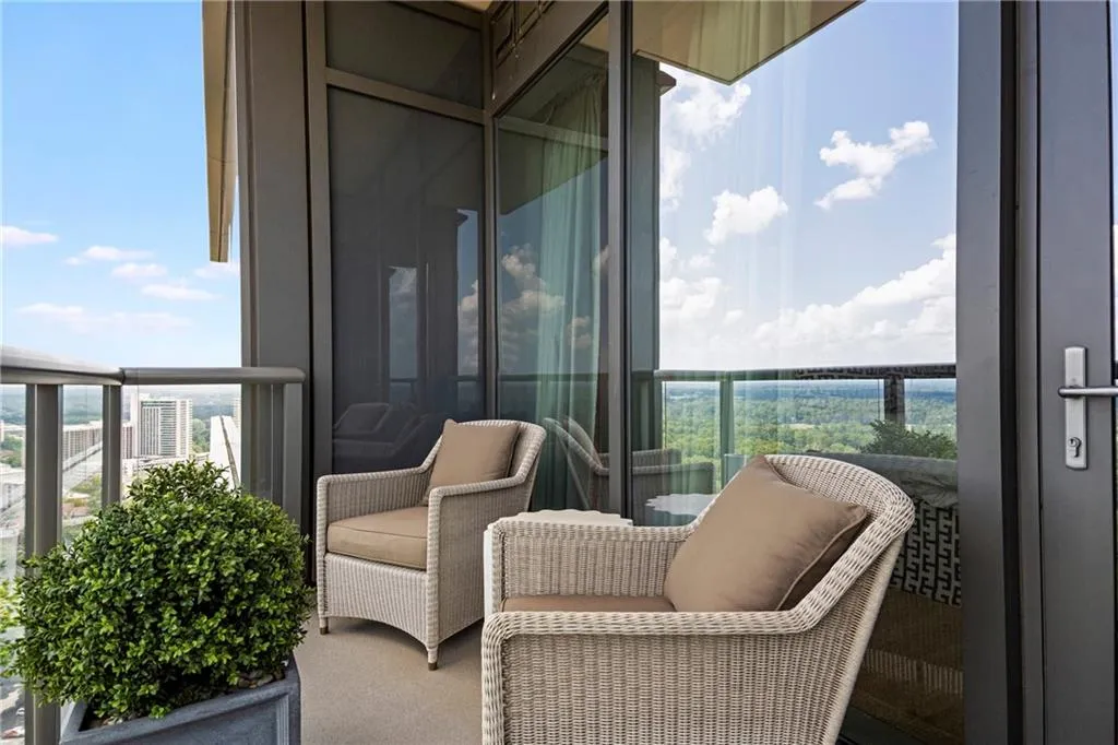 Balcony with glass railing, concrete flooring, exterior glass panels, and a painted metal door frame