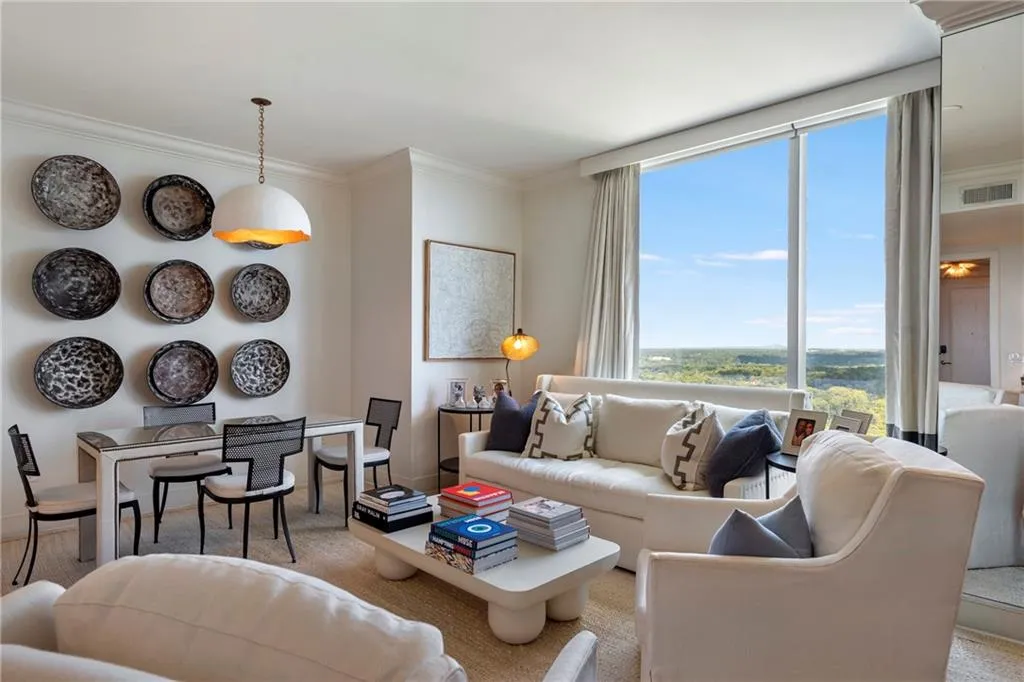 Expansive floor-to-ceiling windows, crown molding, and a contemporary pendant light fixture
