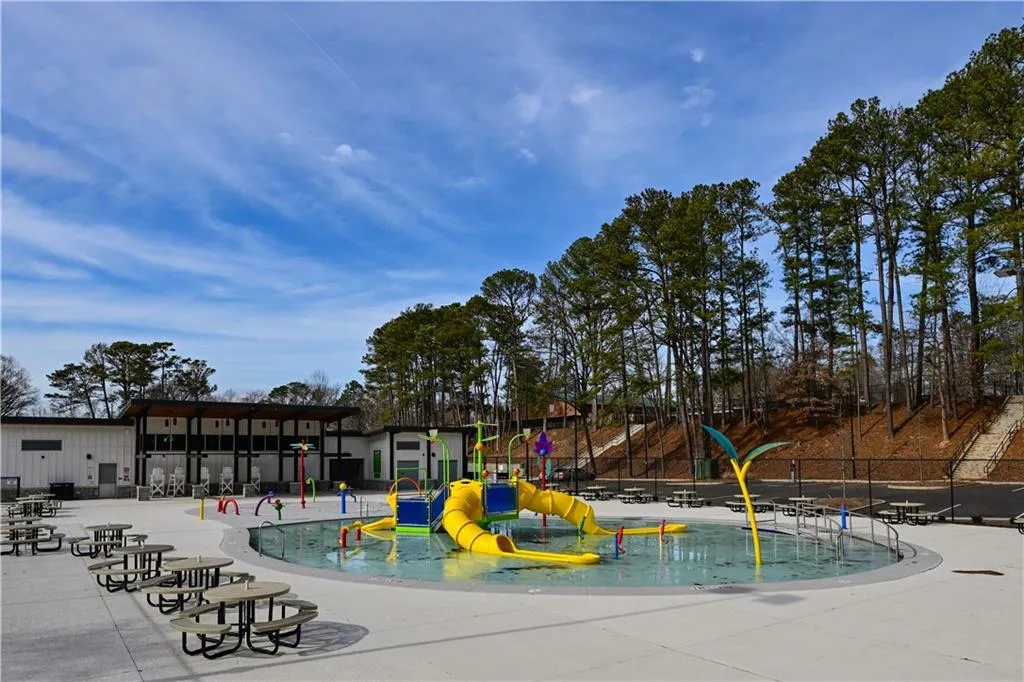View of jungle gym with a water play area, a community pool, and a patio