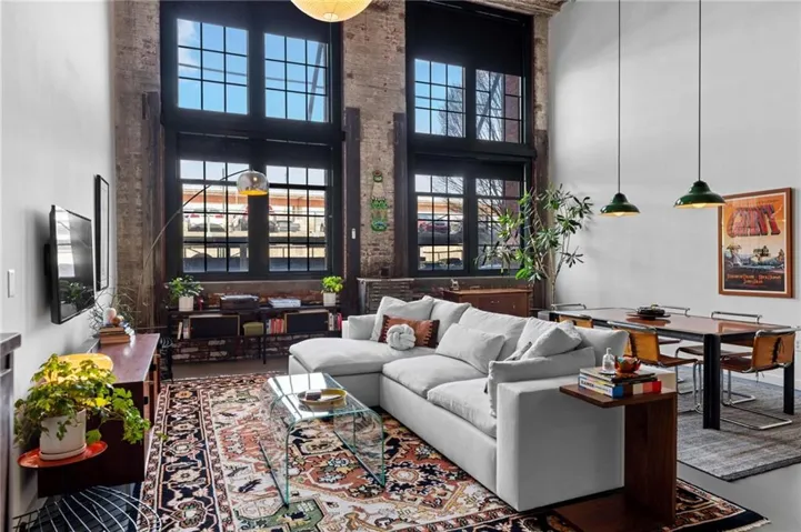 Expansive living area featuring soaring ceilings and exposed brick accents