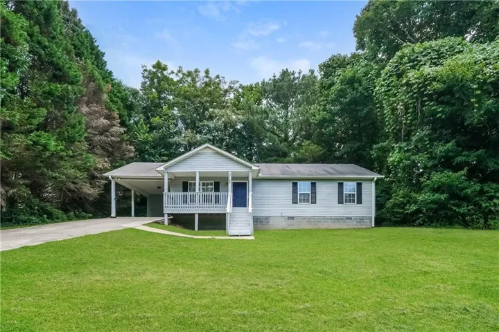 Ranch-style exterior with light blue siding, a covered front porch, and a dedicated carport