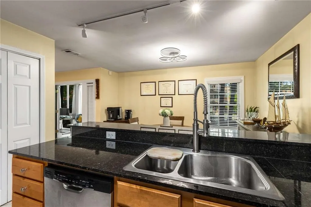 Kitchen featuring stainless steel dishwasher, rail lighting, and brown cabinets