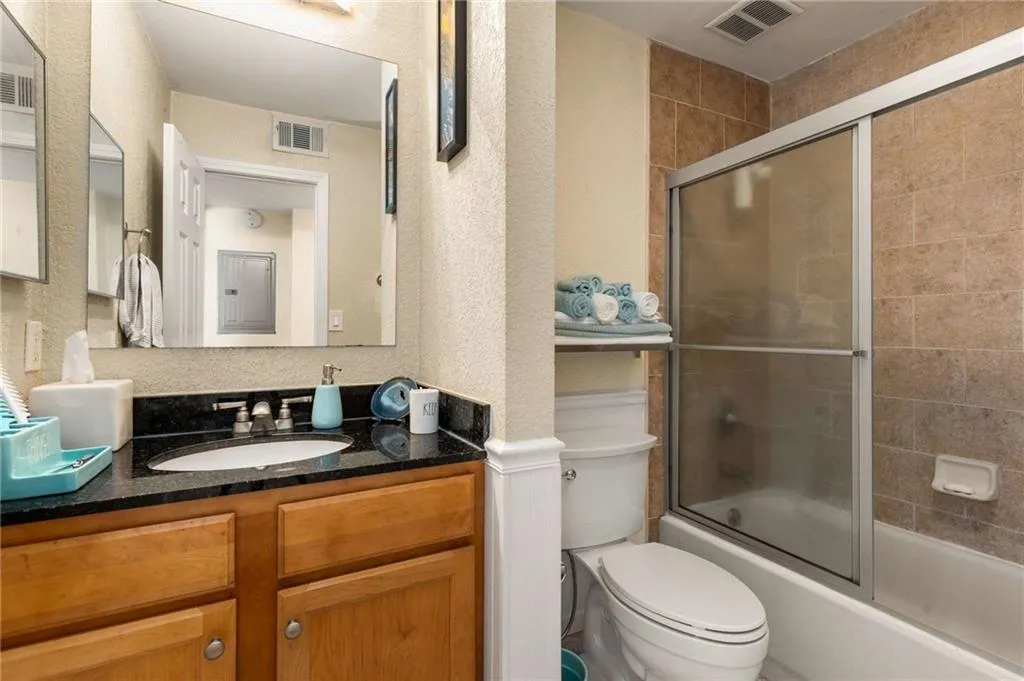Bathroom with vanity, and combined bath / shower with glass door, new toilet and bidet.