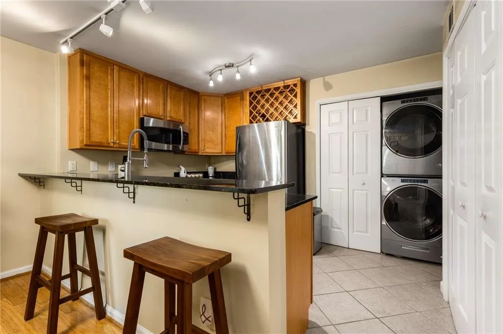 Kitchen featuring stainless steel appliances, stacked washer / dryer,  track lighting, pantry and wine rack