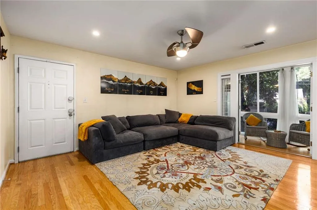 Living area featuring wood finished floors, ceiling fan and view to sunroom.