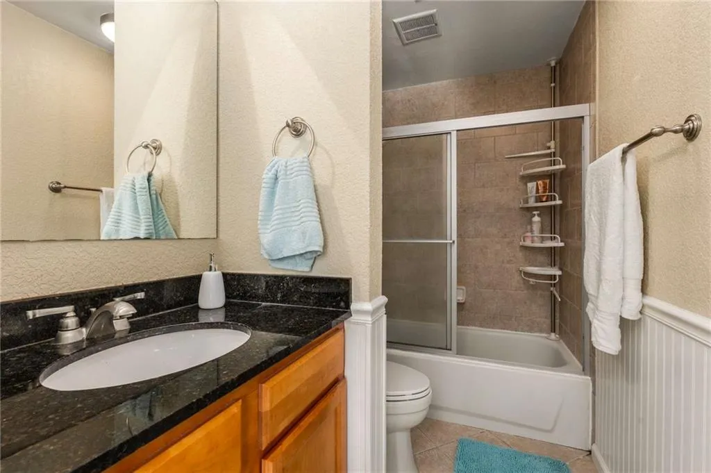 Full bathroom featuring tile patterned floors, vanity, combined bath / shower with glass door, new toilet and bidet