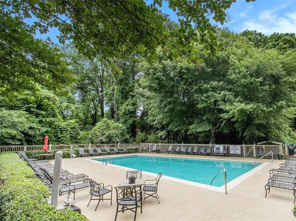 Community pool with a patio area and view of wooded area