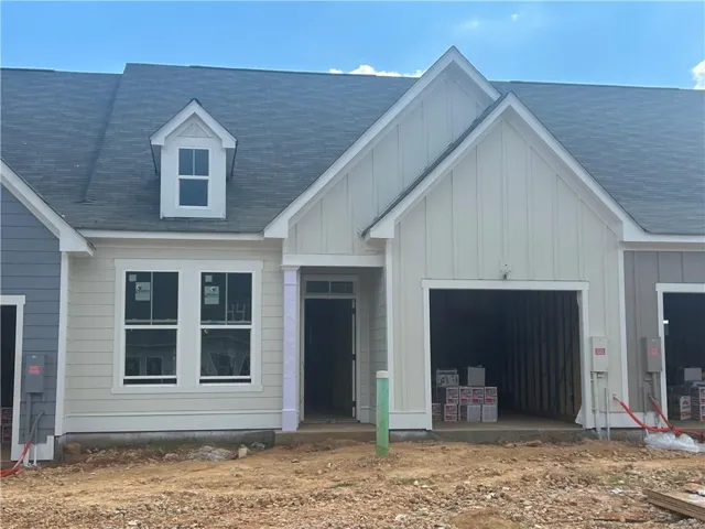 Exterior featuring light-colored horizontal siding, a prominent gable roofline, an integrated garage bay, a dormer window, and a covered entry