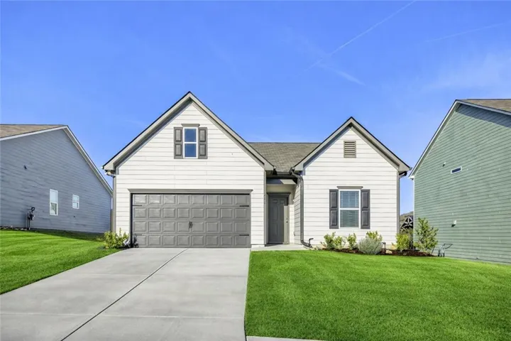 Gable rooflines, a two-car garage with panel detailing, a concrete driveway, and established front landscaping