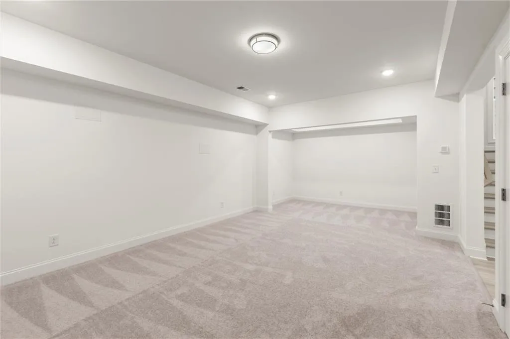 Finished below grade area featuring light carpet, baseboards, and recessed lighting