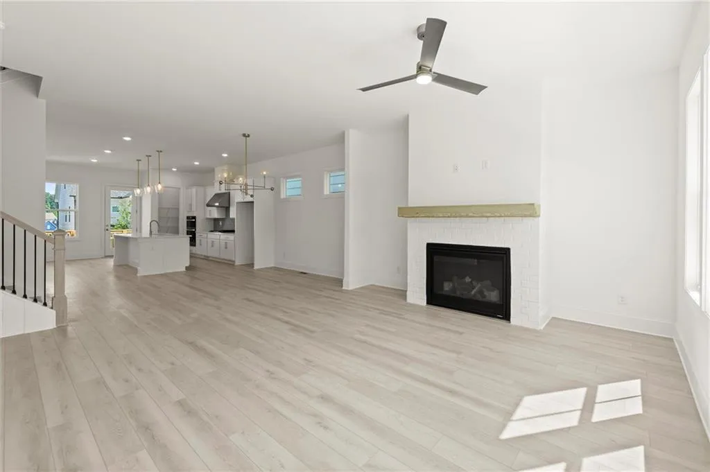 Unfurnished living room featuring a chandelier, a fireplace, recessed lighting, baseboards, and light wood finished floors
