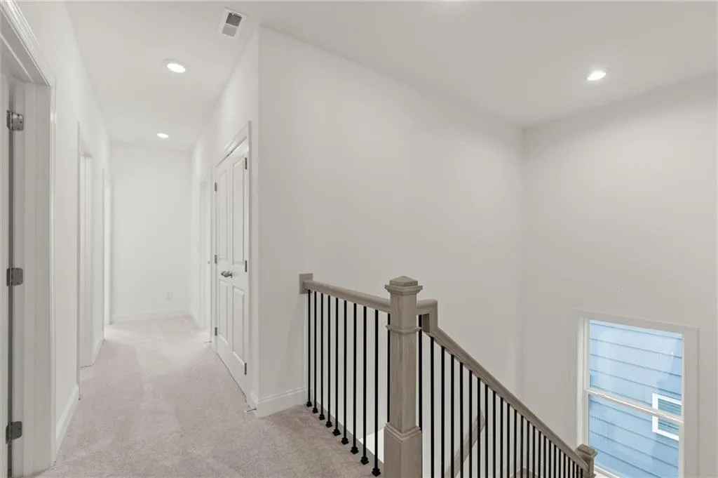 Hall with an upstairs landing, carpet flooring, recessed lighting, and baseboards