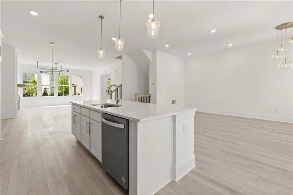 Kitchen with open floor plan, stainless steel dishwasher, a chandelier, a sink, and light wood finished floors