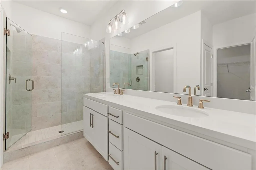 Bathroom featuring a stall shower, double vanity, tile patterned flooring, a spacious closet, and recessed lighting