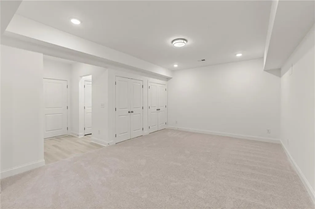 Basement featuring light carpet, baseboards, and recessed lighting